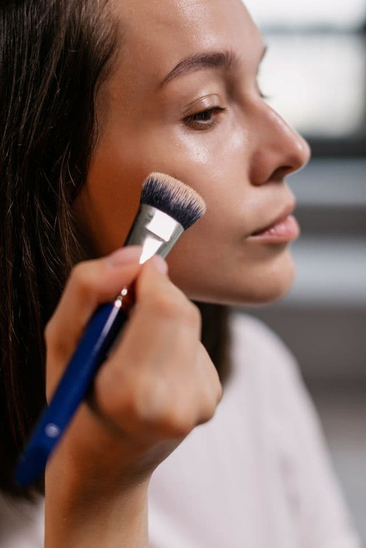 Woman applying makeup with a brush that can collect skin oil and residue 