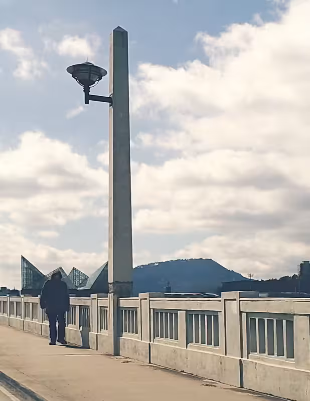 Man walking across a bridge on a cold day