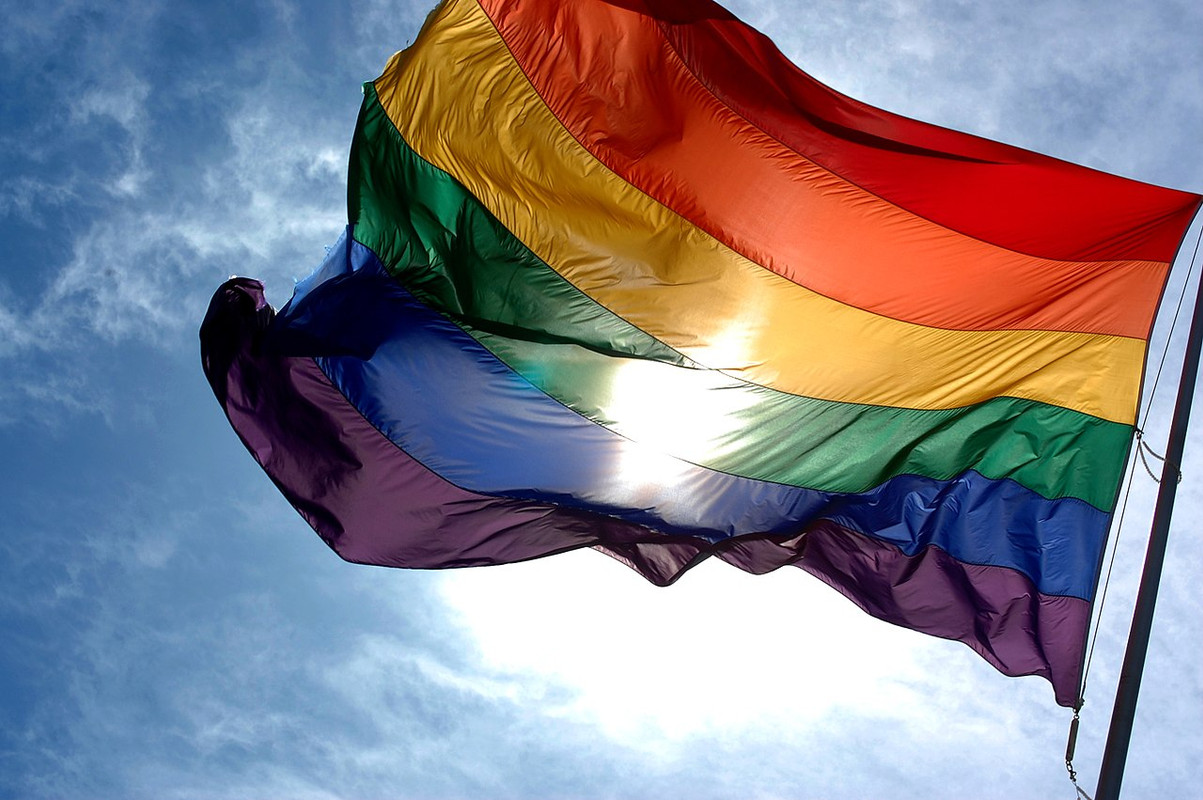 1280px-Rainbow_flag_and_blue_skies