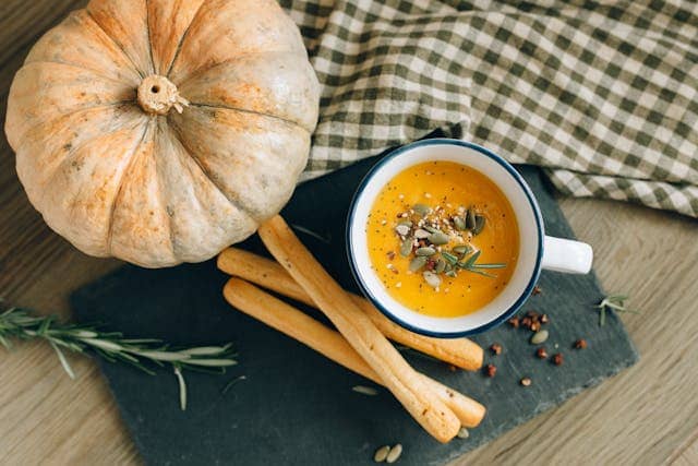 Pumpkin with pumpkin soup and crackers placed on a table