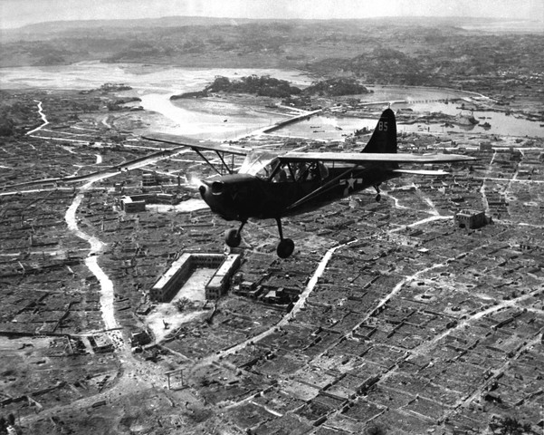 Un avión de observación de la Marina vuela sobre Naha, capital de Okinawa. En este vuelo, la pequeña nave atrajo el fuego antiaéreo de la ciudad que estaba en control japonés en ese momento. Mayo de 1945 Un avión de observación de la Marina vuela sobre Naha, capital de Okinawa. En este vuelo, la pequeña nave atrajo el fuego antiaéreo de la ciudad que estaba en control japonés en ese momento. Mayo de 1945