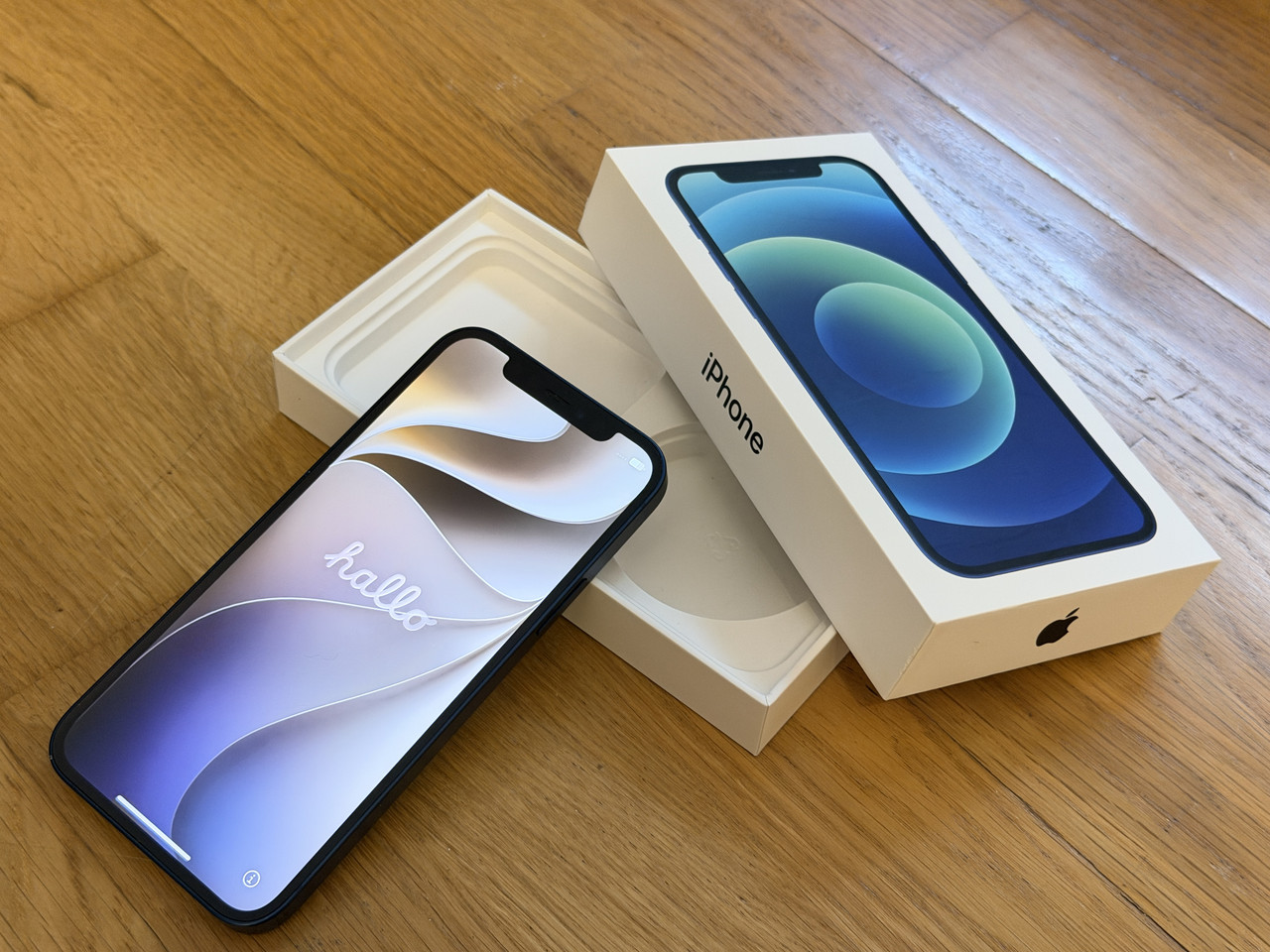 iPhone mit eingeschaltetem Display und Originalverpackung