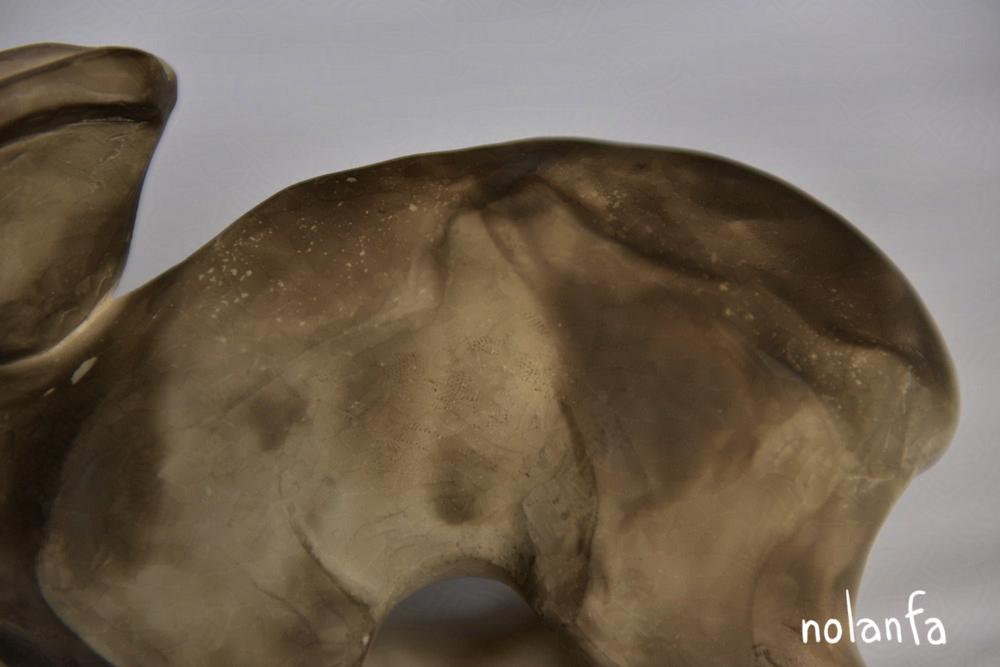 the back of a clay sculpture of a hare with lighter color in a splatter-like pattern