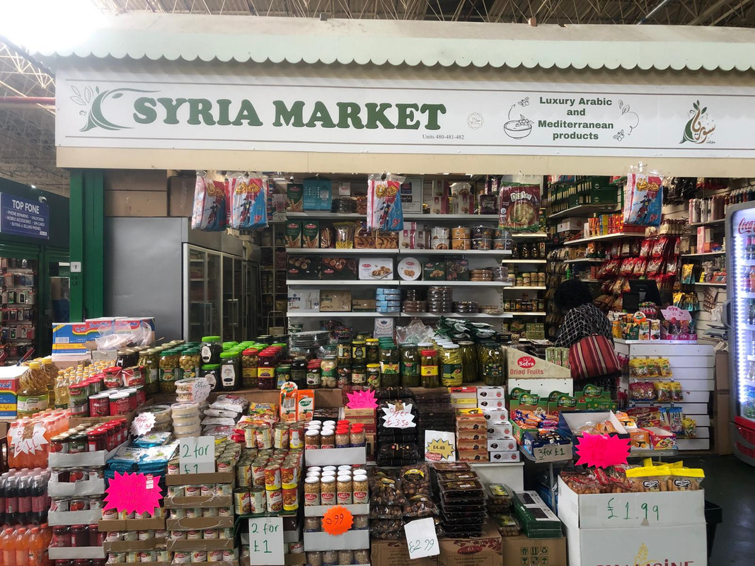 A syrian marketstall inside Leeds Makrket with store cupboard goods stacked high on shelves.
