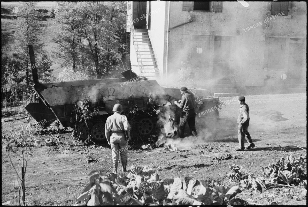 Une automitrailleuse semi-chenillée allemande Sd.Kfz 251 vient de sauter sur une mine dans le villag