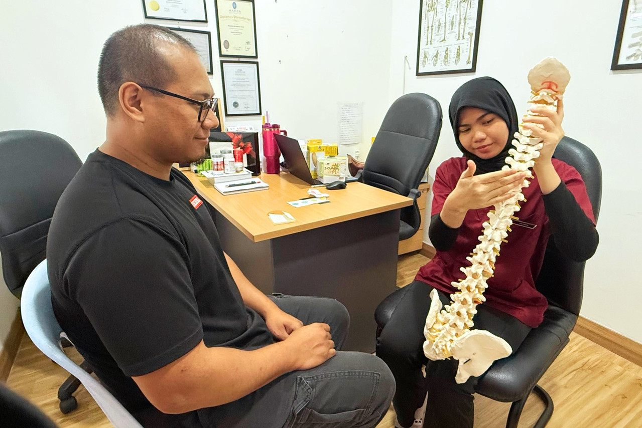 Terapis Iswanah membantu pesakit dengan teknik manual di klinik Cheng