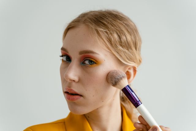 a woman adding warmth, blush, and definition to her face according to fall makeup trends 