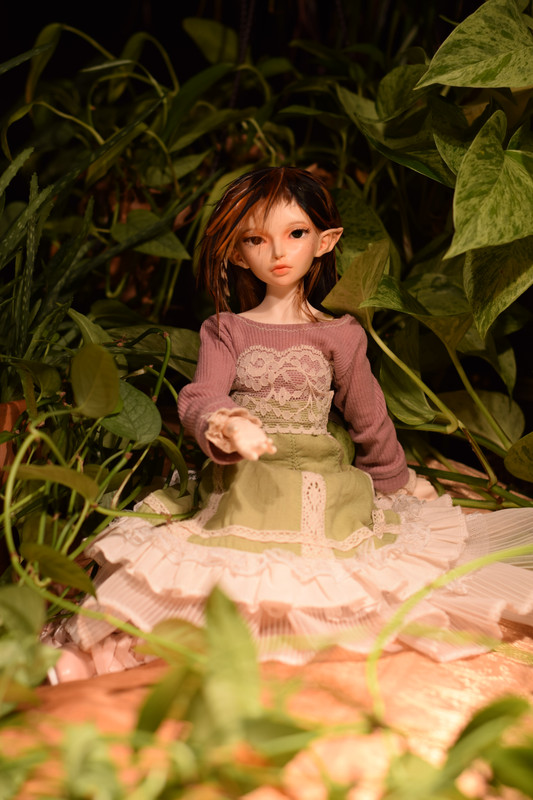 Aria surrounded by plants, holding out her hand invitingly