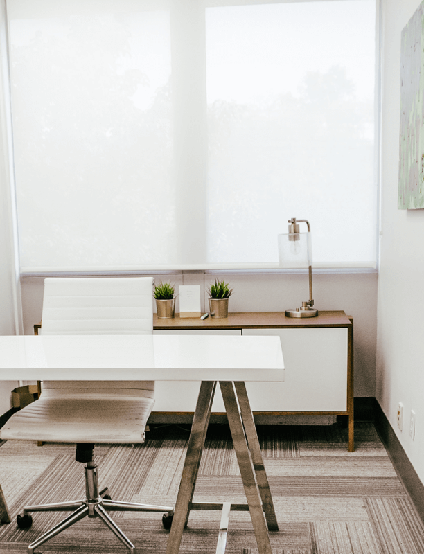 Bright coworking space kitchenette area with a high table and stools.