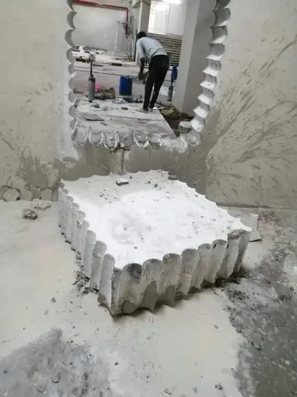 عامل يرتدي معدات السلامة ويشغل آلة منشار جداري كبيرة.