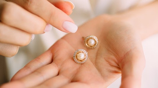 A girl holding pearl embedded stud earring in her hand