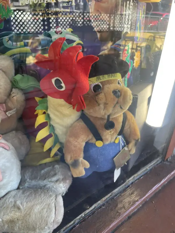 two plushes: one of a seal with a little captain's outfit, and the other a rooster with sly eyes, leaning over the shoulder of the first.