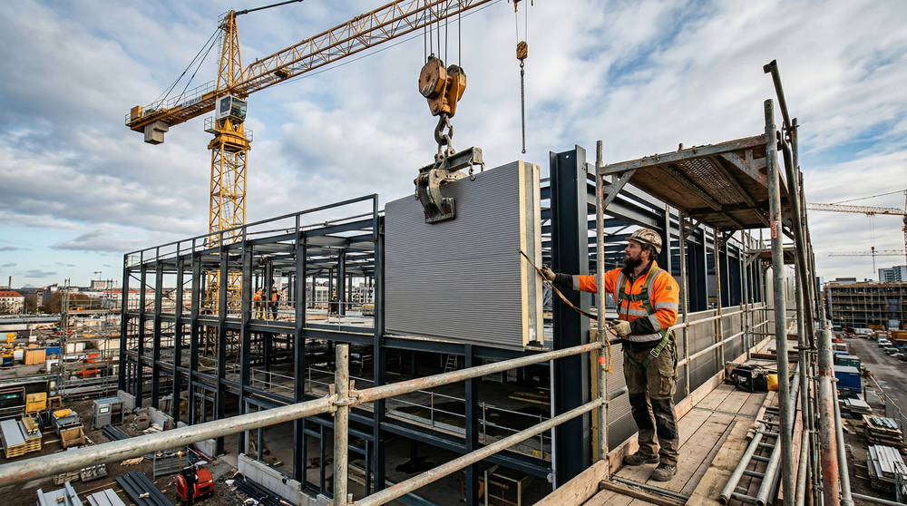 Монтаж стеновой сэндвич-панели башенным краном на стальной каркас здания, демонстрация точности позиционирования при высокой парусности материалов