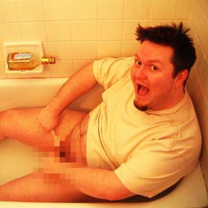 Man sitting in a bathtub holding a plastic knife