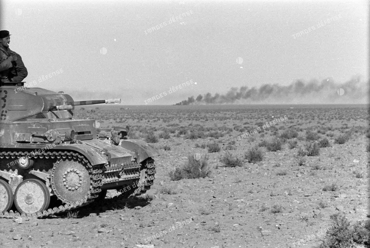 Un char Panzer II (Pz-II) du Panzer-Regiment 8 (Pz.Rgt-8) dans le désert, au loin un nuage de fumée 