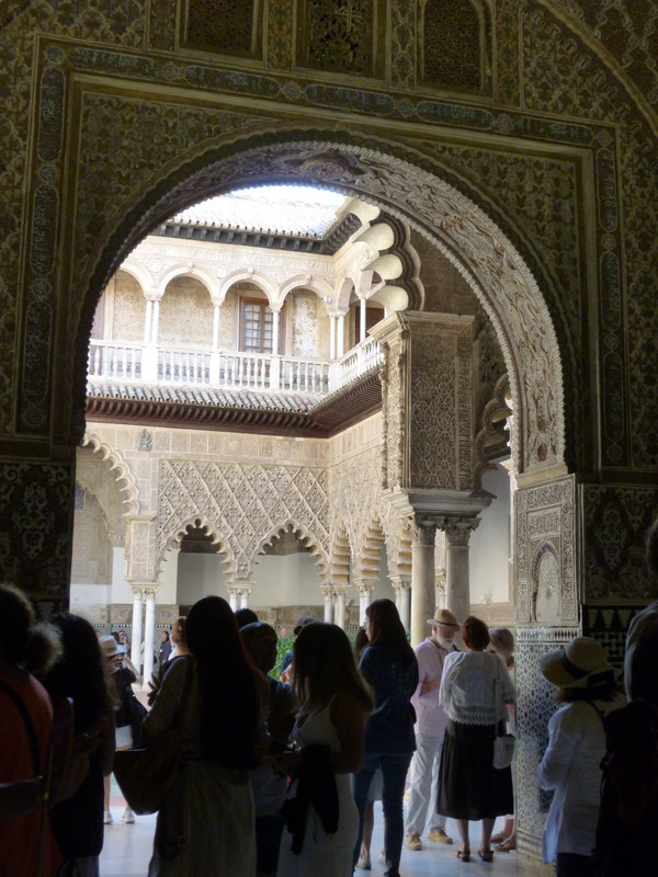 Carved archway.  This time the stones are inlaid in red and blue.  More carved arches are seen in the background, surrounding another courtyard.  The people in the front are being used to demonstrate how busy it was.