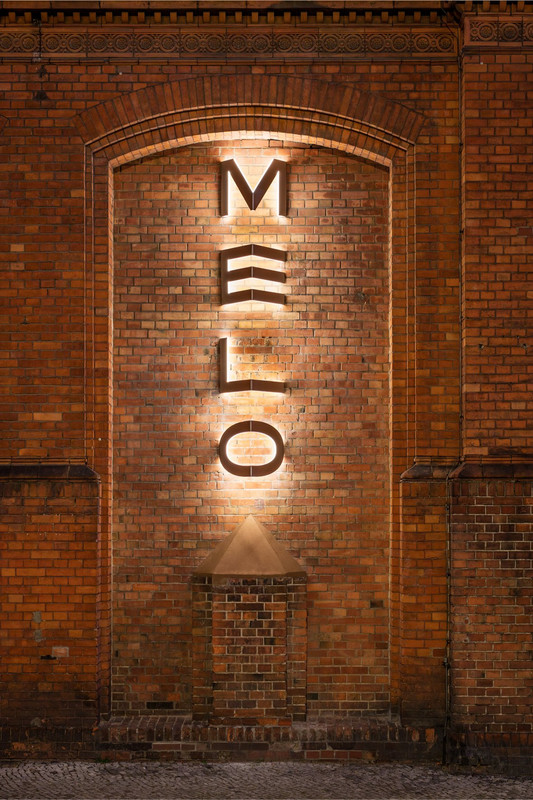 Backlit MELO lettering on a historic brick façade in Berlin