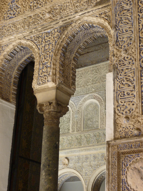 Carved stone arch in the foreground, from a cream coloured stone, with blue inlays.  In the background is a carved stone wall, again with blue inlays but it looks much paler because it is further away