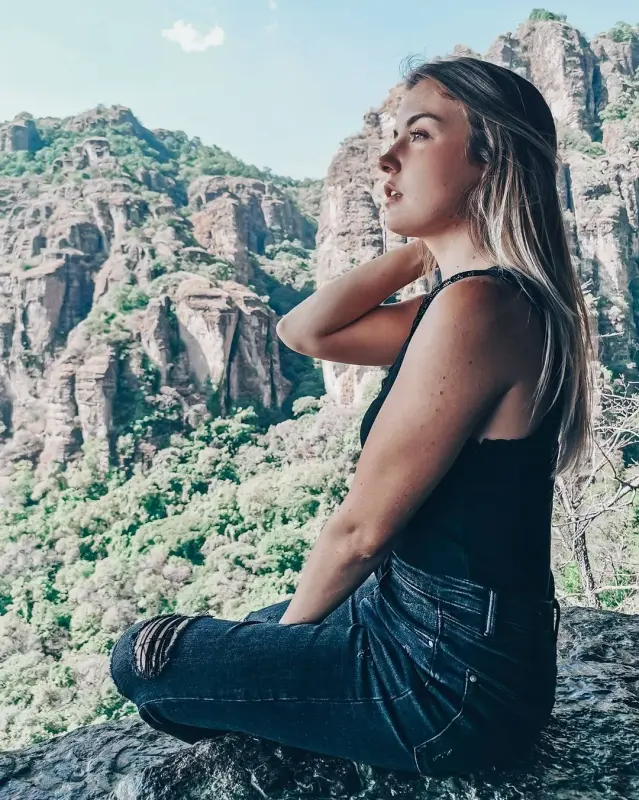 Chica francesa sentada sobre unas rocas mirando la hermosa naturaleza que la rodea