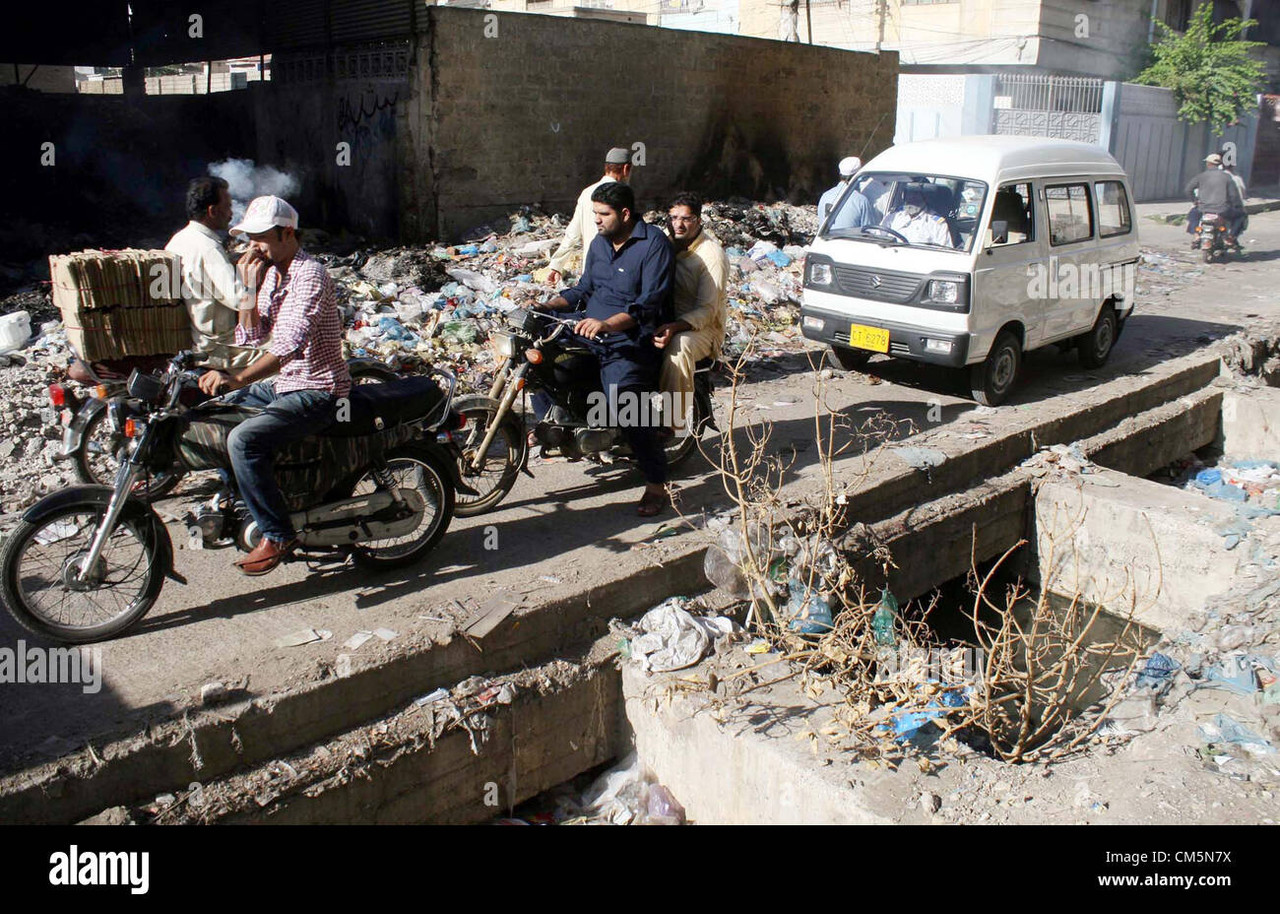 commuters pass through near an open sewerage drain and huge heap of CM5N7X