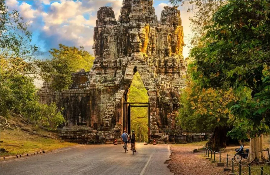 Ancient stone gate of Angkor Wat leading into the temple complex surrounded by trees.