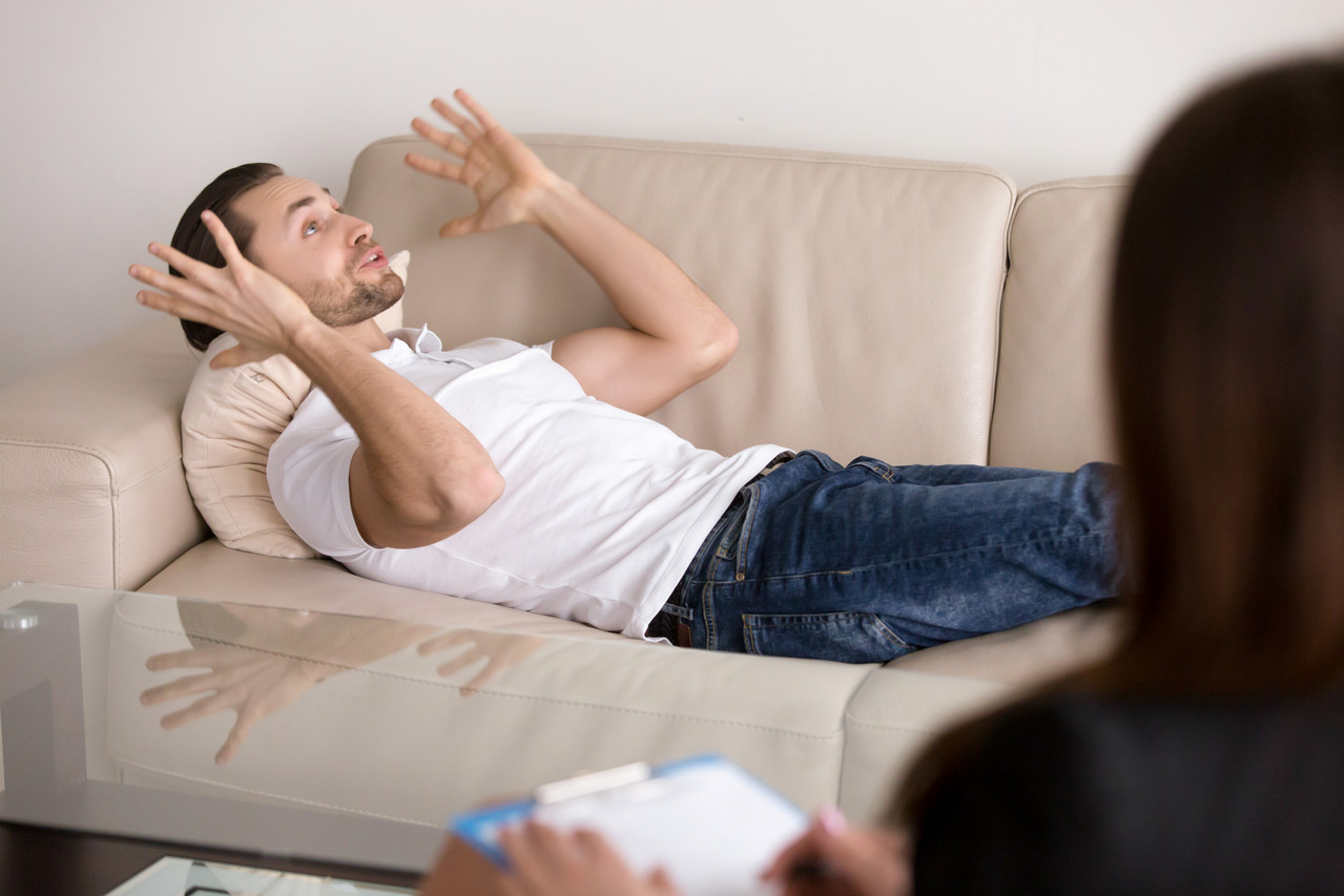 young male patient lying couch talking female psychologist