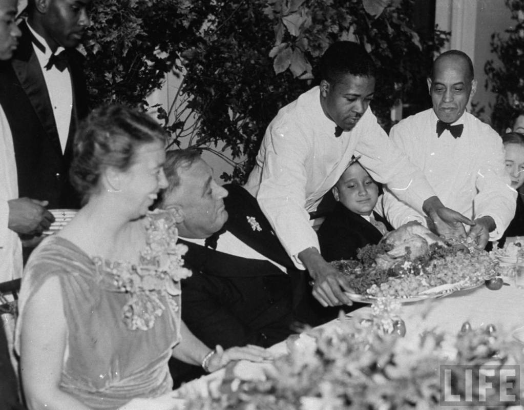 El presidente Franklin D. Roosevelt se aparta mientras un camarero pone el pavo sobre la mesa durante la cena de Acción de Gracias en 1937