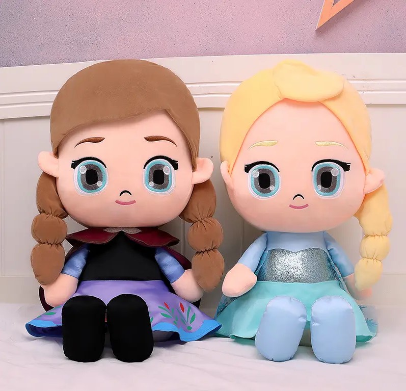 Two stuffed dolls sitting on a bed Description automatically generated