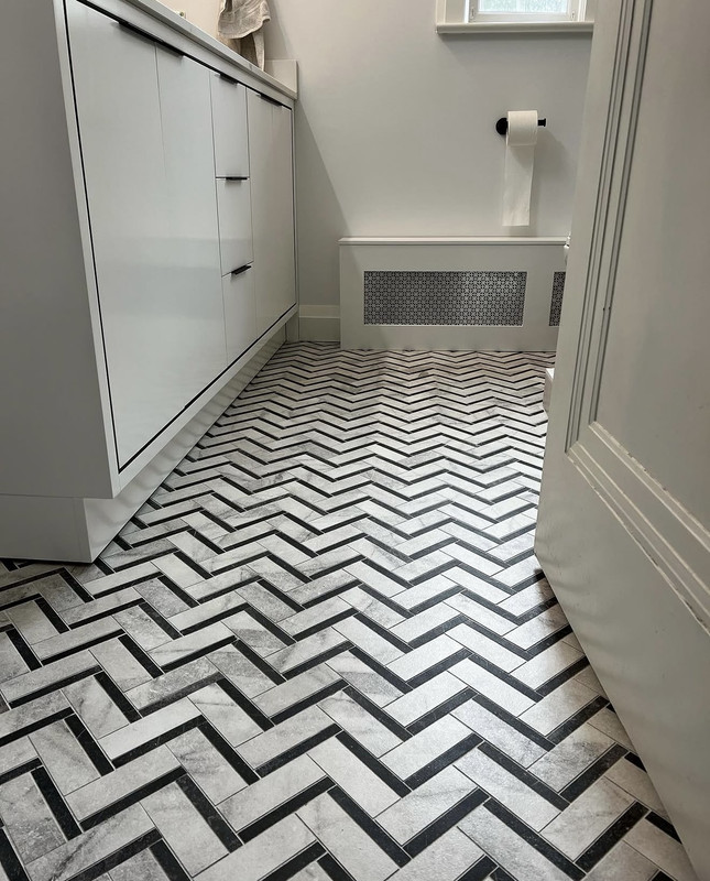 Close-up of bordered herringbone floor — marble-look tile with charcoal liner strips