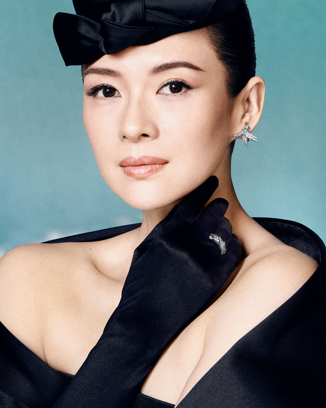 Zhang Ziyi con Gioielli Tiffany Bird on a Rock Primo piano dell'attrice Zhang Ziyi, con un guanto nero, anello di diamanti, orecchino a forma di uccello di Tiffany e un cappellino nero, sullo sfondo blu del cielo