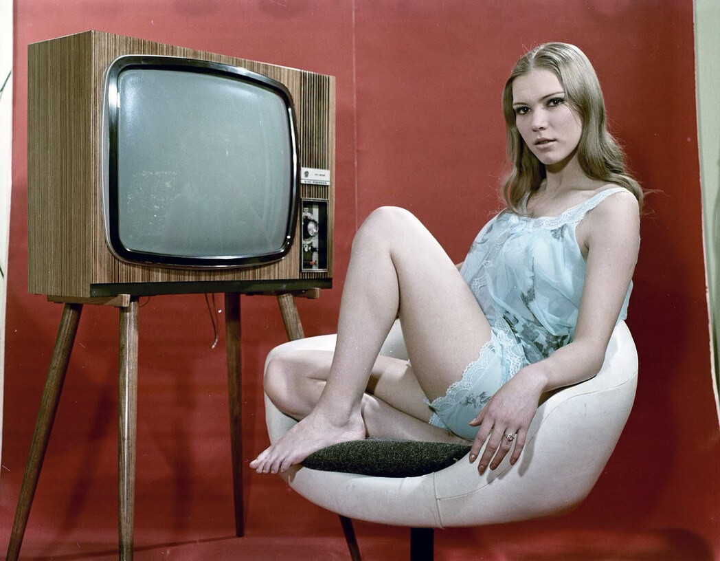 1973 Hungarian Studio Advert: Model posing barefoot in a white tulip chair next to an Orion Victoria television