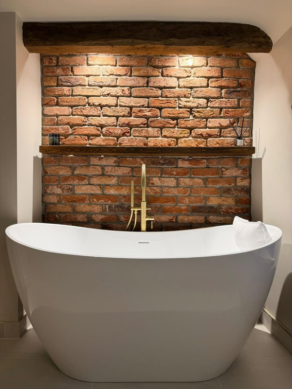 Close up freestanding bath and exposed brick wall