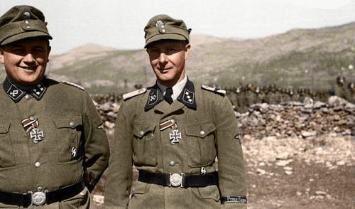 Oficiales de la 7ª División SS de Montaña Prinz Eugen delante del resto de sus tropas en formación tras ellos