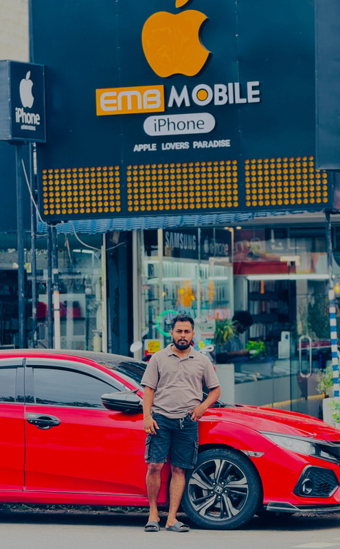 V.G. Sithum Gamage — Founder and Owner of EMB Mobile, standing proudly in front of the store signboard