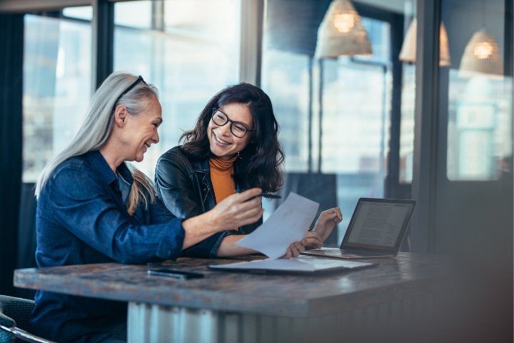 Two coworkers chatting in a conference room while seated