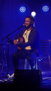 Ailton Souza sorrindo durante apresentação de voz e violão