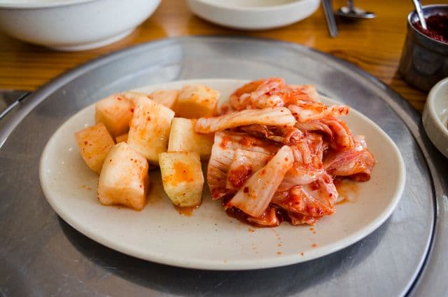Plate of sauerkraut and kimchi, two fermented foods rich in probiotics that help support gut health and digestion.