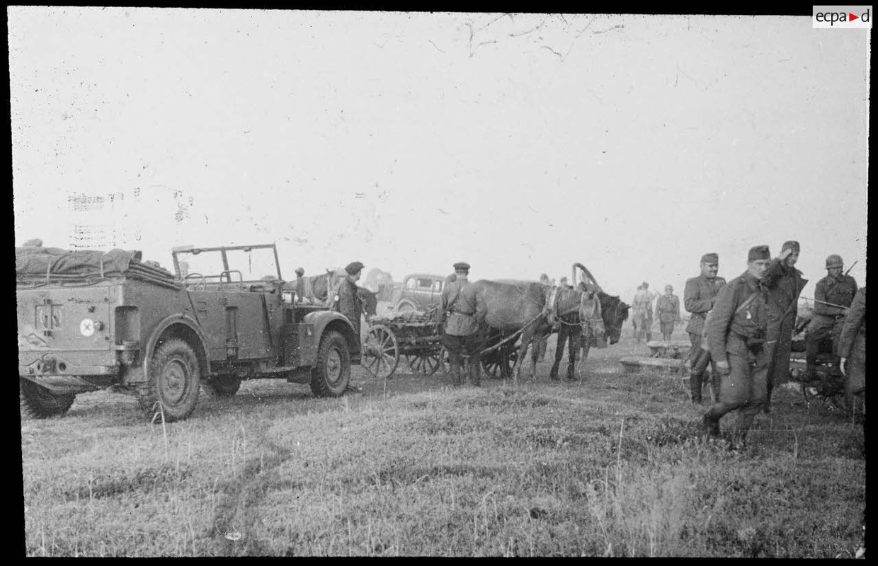 Des officiers allemands à bord d'un véhicule Horch Kfz.15 s'adressent à des hommes à cheval. Insigne