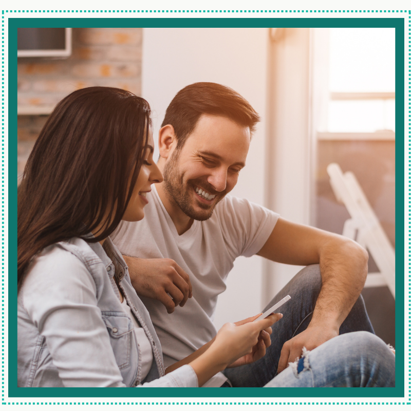 Couple smiling while using the Heal@Home recovery app on a smartphone