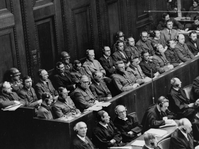 Demandados sentados bajo custodia en el banquillo de los abogados defensores durante el juicio a los doctores