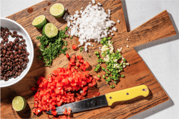 wooden cutting board with chopped taco veggie ingredients on top