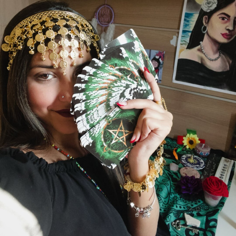 A stylized photo of Cartomante Nicolly holding tarot cards in a mystical setting.