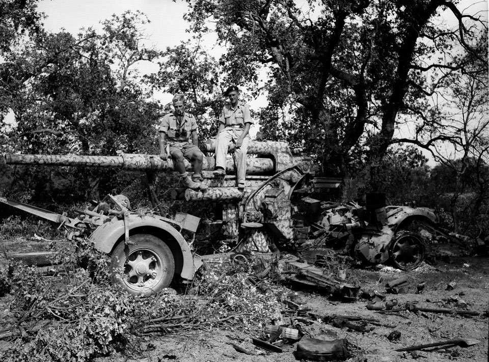 Two members of 3rd County of London Yeomanry (Sharpshooters) sit astride a knocked out German 88 mm 