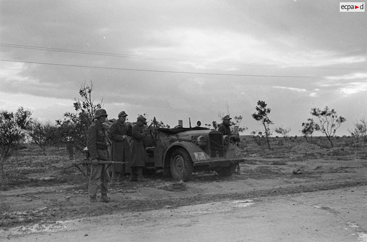 Une voiture Horch Kfz-16 garée au bord de la via Balbia, au milieu d'arbustes rachitiques, est entou