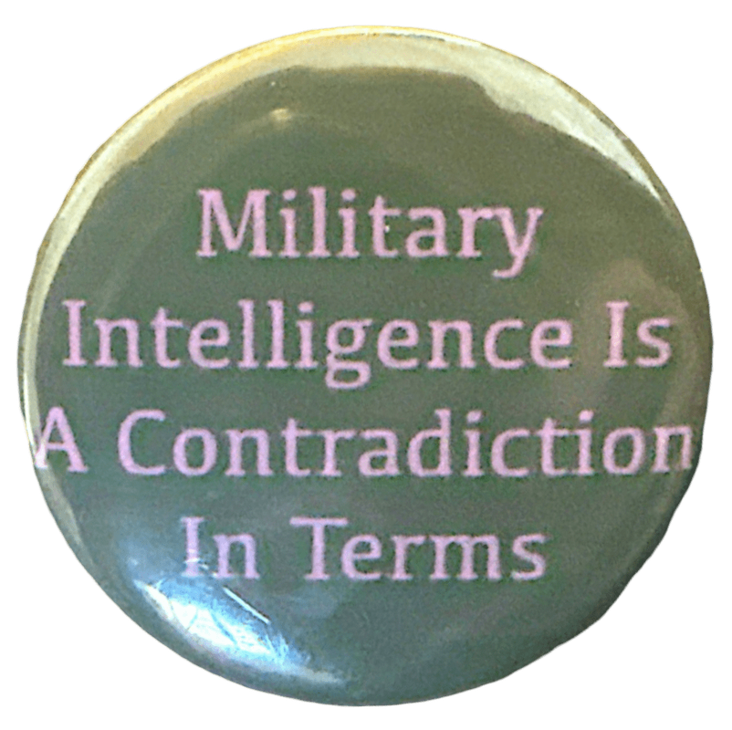 a gray-green pin with purple text that says 'Military Intelligence Is A Contradiction in Terms'