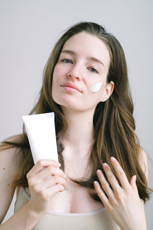 a woman applying sunscreen to keep her skin protected in fall 