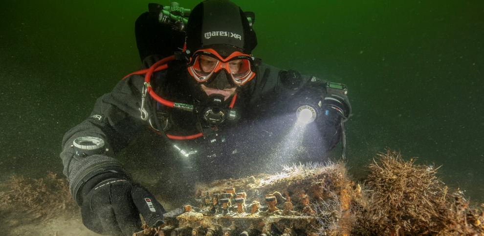 Uno de los buzos, junto a la máquina Enigma. Efe