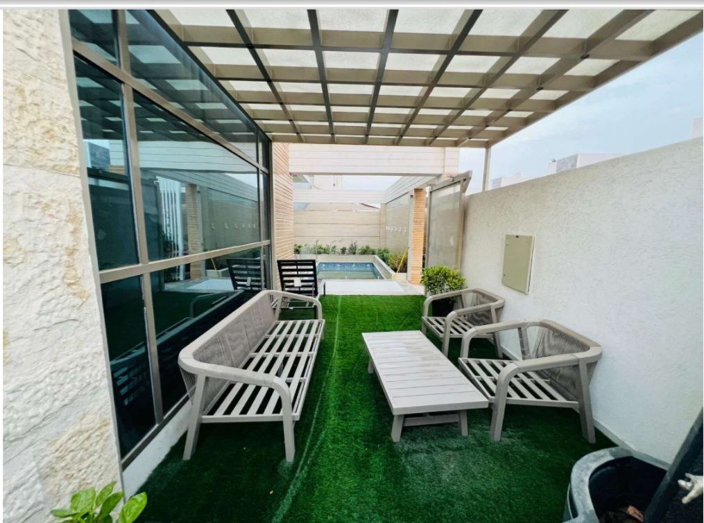 مجلس عشبي أنيق بجانب المسبح في فيلا فاخرة بعجمان، يوفر مساحة خارجية مريحة للاستجمام والاستمتاع بالأجواء الهادئة.