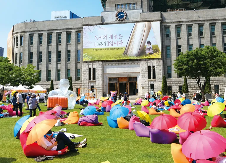 조용하고 따뜻한 분위기의 도서관 열람실, 책상에 책과 노트북이 놓인 공부 공간
