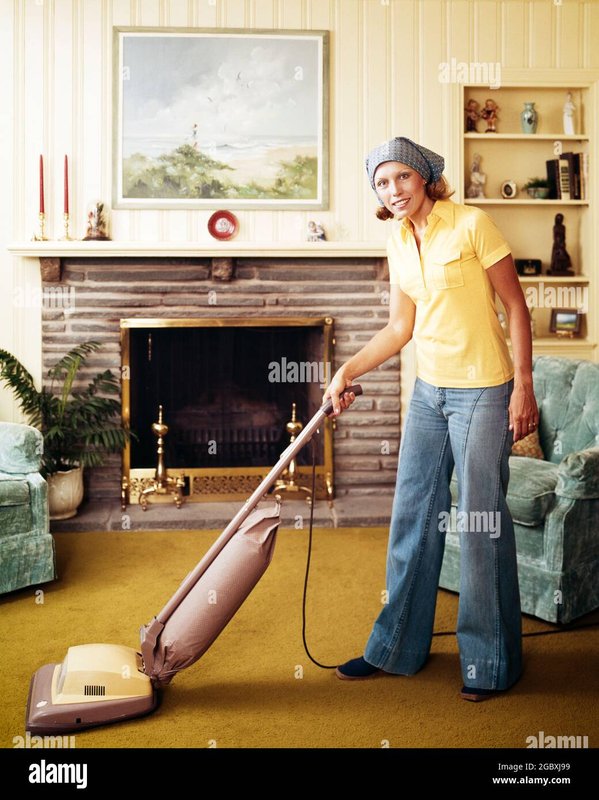 1970s-woman-housewife-wearing-bell-bottom-jeans-yellow-t-shirt-headscarf-vacuuming-living-room-using.jpg